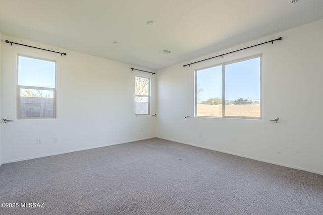 unfurnished room with carpet floors, visible vents, and baseboards