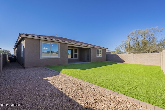 rear view of house featuring a patio area, a fenced backyard, a yard, and stucco siding