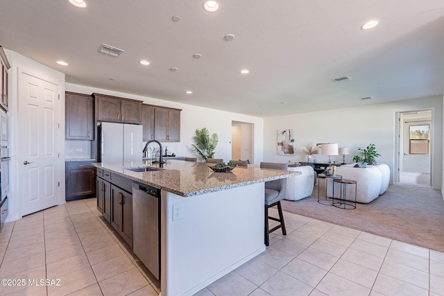 kitchen featuring light carpet, visible vents, appliances with stainless steel finishes, light stone counters, and a sink