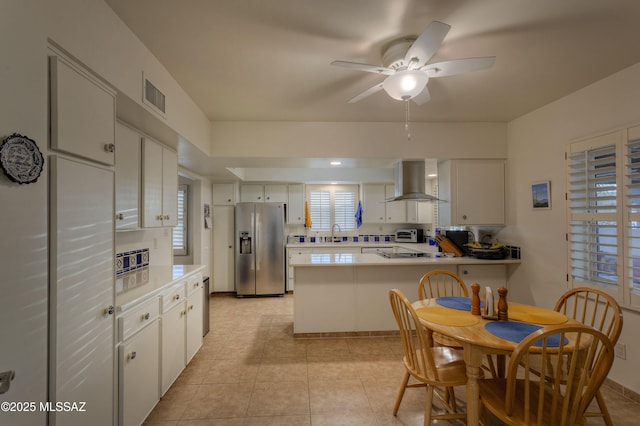 kitchen featuring range hood, white cabinetry, ceiling fan, kitchen peninsula, and stainless steel refrigerator with ice dispenser