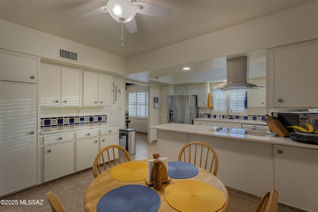 kitchen with white cabinetry, island range hood, ceiling fan, and stainless steel fridge with ice dispenser