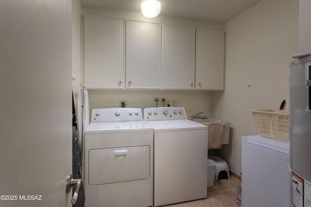 washroom featuring water heater, cabinets, independent washer and dryer, and light tile patterned flooring