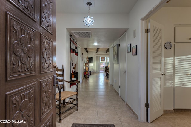 hallway featuring light tile patterned floors and beamed ceiling