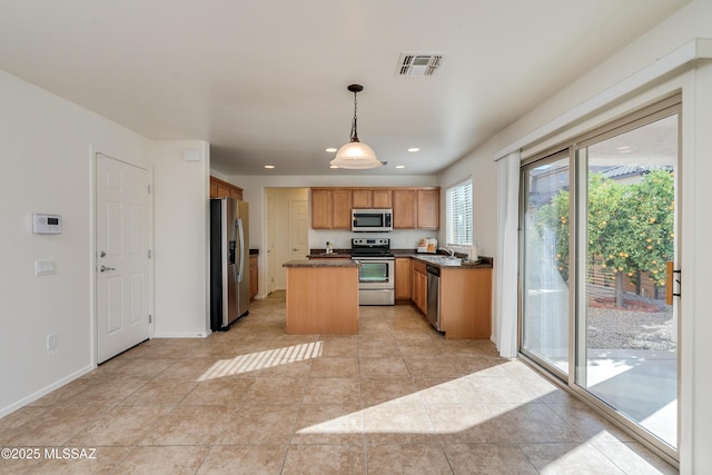 kitchen featuring appliances with stainless steel finishes, sink, a kitchen island, hanging light fixtures, and light tile patterned flooring