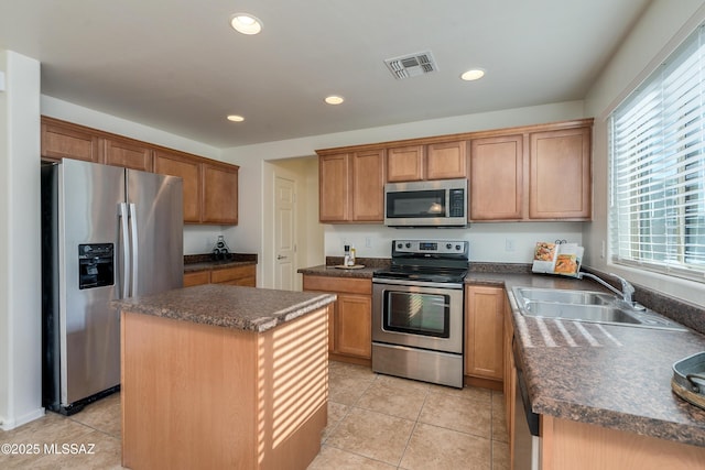 kitchen with appliances with stainless steel finishes, a center island, light tile patterned floors, and sink