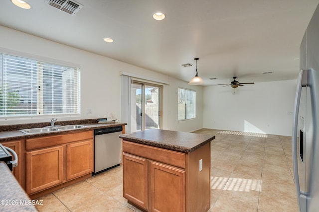 kitchen with appliances with stainless steel finishes, ceiling fan, sink, a kitchen island, and hanging light fixtures