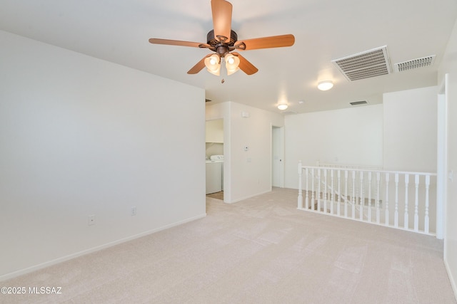 empty room featuring washer / clothes dryer, ceiling fan, and light colored carpet