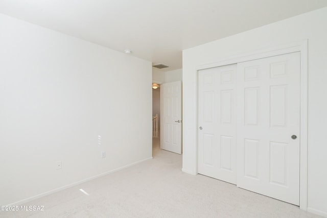 unfurnished bedroom featuring light colored carpet and a closet