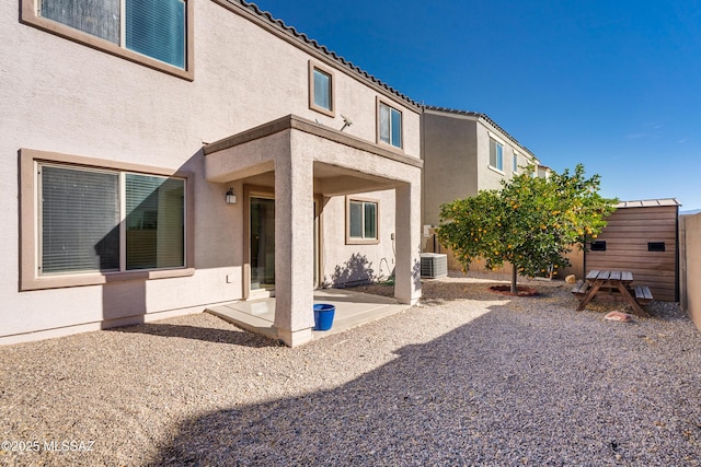 rear view of property featuring a patio area, central air condition unit, and a storage shed