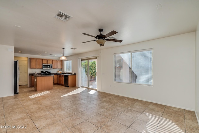 kitchen with a kitchen island, light tile patterned flooring, decorative light fixtures, and appliances with stainless steel finishes