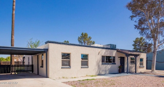 view of front of home featuring a carport, concrete driveway, fence, and stucco siding