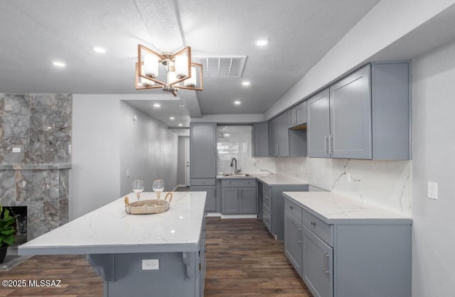 kitchen featuring tasteful backsplash, sink, a fireplace, a center island, and gray cabinets