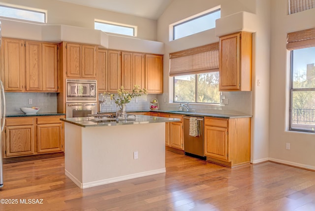 kitchen featuring decorative backsplash, light hardwood / wood-style flooring, a kitchen island, and appliances with stainless steel finishes