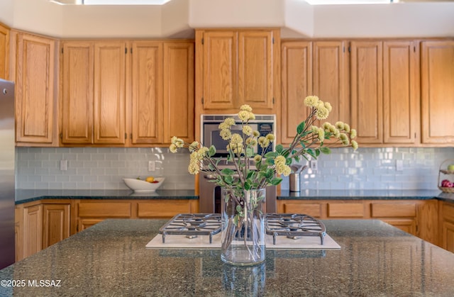 kitchen with decorative backsplash, appliances with stainless steel finishes, and dark stone counters