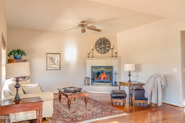 living room featuring hardwood / wood-style floors, ceiling fan, and a tile fireplace