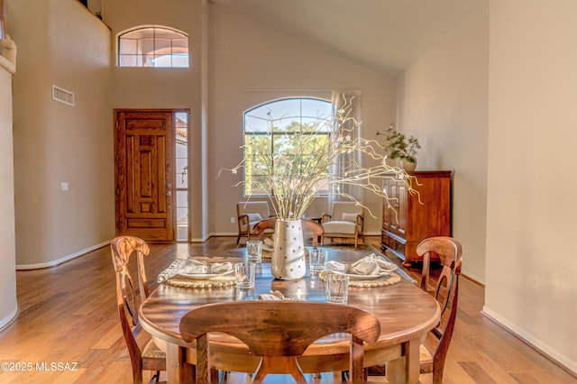 dining room featuring wood-type flooring and high vaulted ceiling