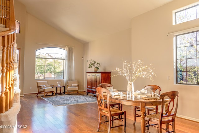 dining space with wood-type flooring and high vaulted ceiling