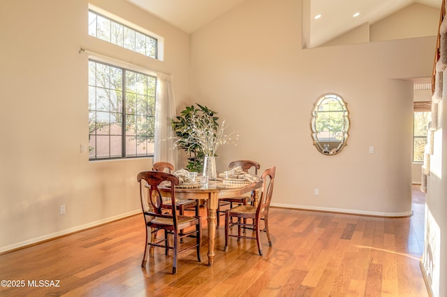 dining room featuring high vaulted ceiling and light hardwood / wood-style flooring