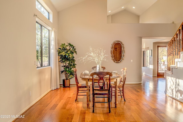 dining area with light wood-type flooring and high vaulted ceiling