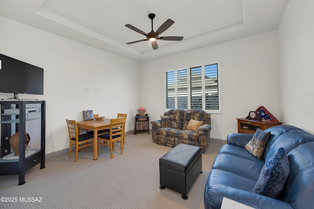 carpeted living room with a tray ceiling and ceiling fan