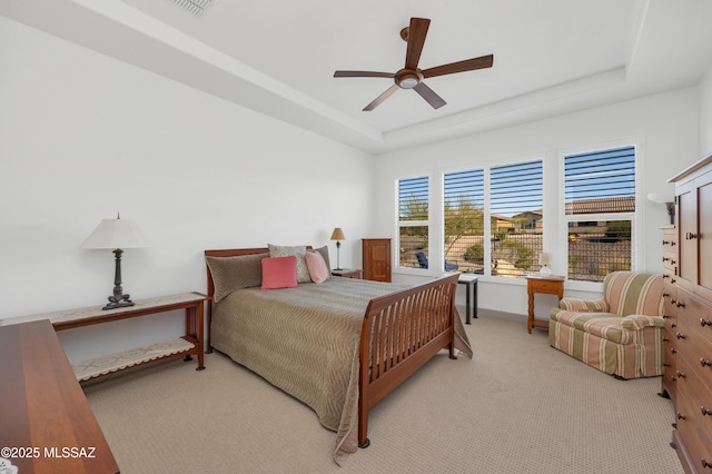 carpeted bedroom with ceiling fan and a tray ceiling