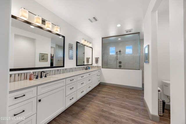 bathroom featuring a tile shower, vanity, hardwood / wood-style flooring, and toilet