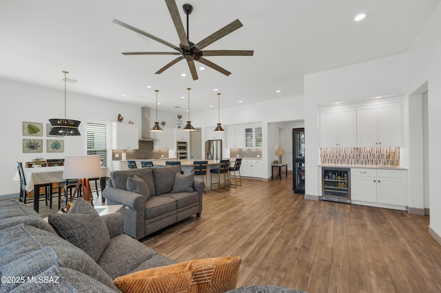 living room featuring wine cooler, ceiling fan, hardwood / wood-style flooring, and indoor wet bar