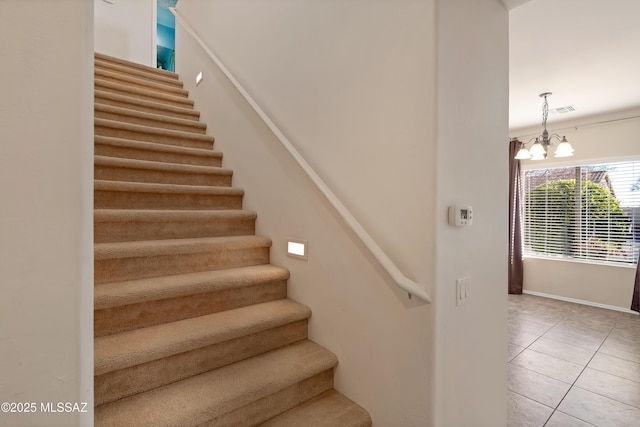 staircase featuring tile patterned flooring and a chandelier