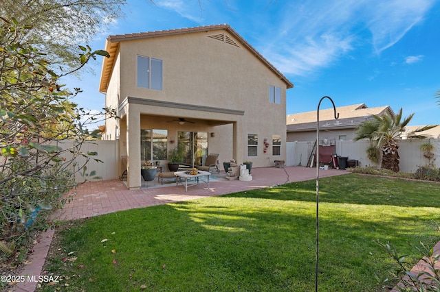 back of property with a yard, ceiling fan, and a patio area