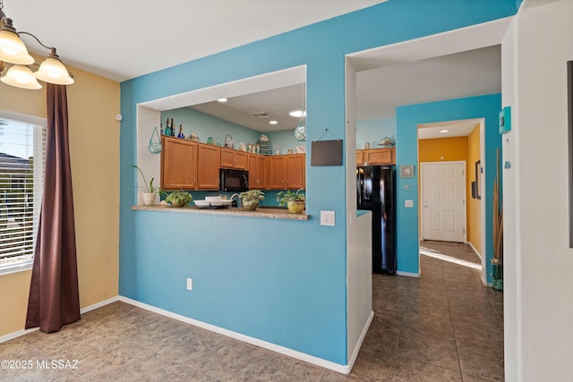 kitchen featuring kitchen peninsula, pendant lighting, and black appliances