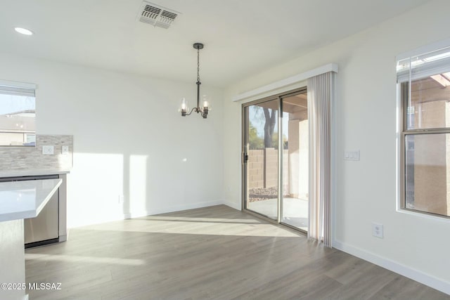 unfurnished dining area featuring a notable chandelier and light wood-type flooring