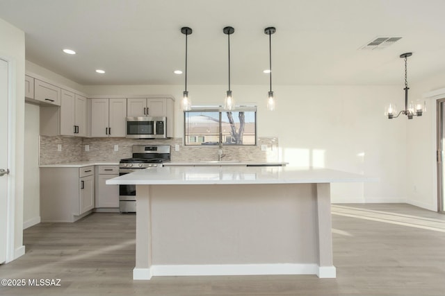 kitchen with visible vents, light wood finished floors, light countertops, appliances with stainless steel finishes, and tasteful backsplash