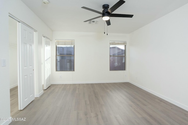 spare room featuring ceiling fan, a healthy amount of sunlight, and light hardwood / wood-style floors