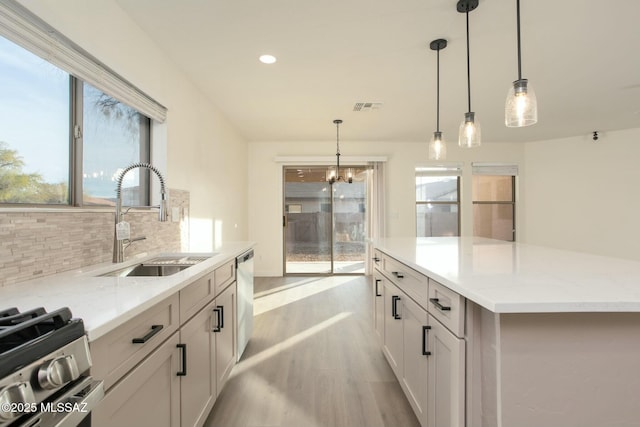 kitchen with visible vents, backsplash, light wood-style floors, stainless steel appliances, and a sink