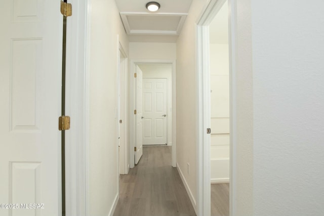 corridor featuring attic access, wood finished floors, and baseboards