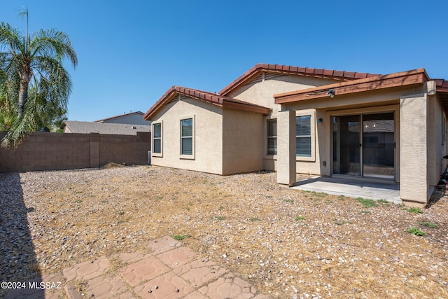 rear view of property with stucco siding, a patio, a tile roof, and fence