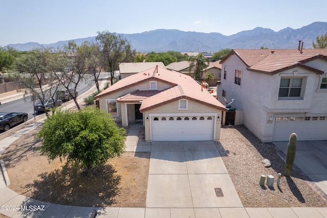 view of front of property featuring driveway, an attached garage, stucco siding, a tile roof, and a mountain view