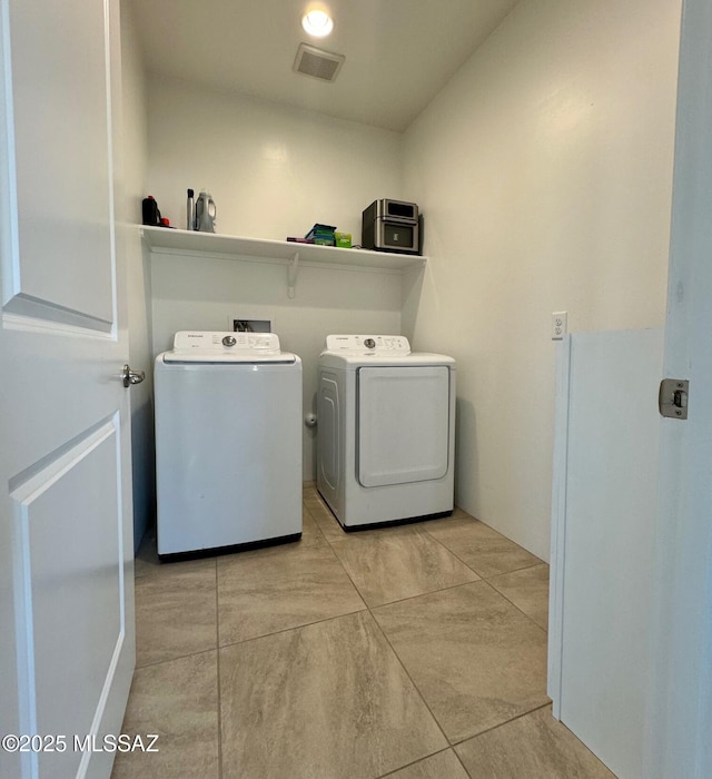 laundry area with washing machine and dryer and light tile patterned floors