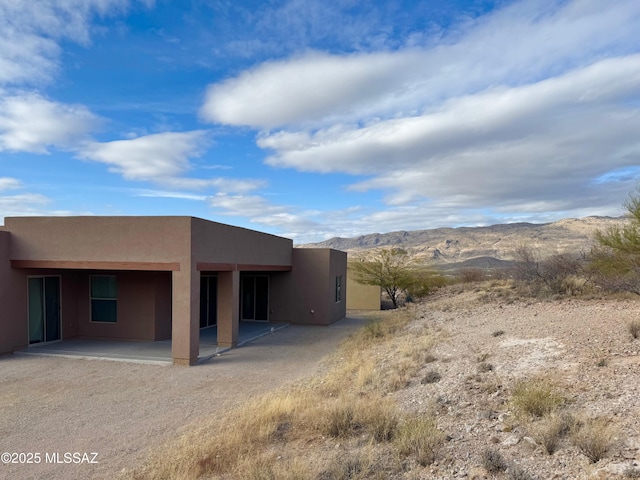 rear view of house featuring a mountain view and a patio area