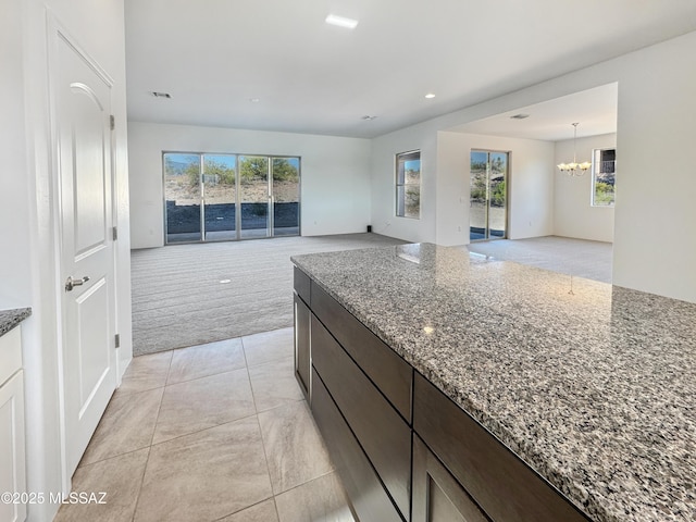 8015 S Galileo Ln, Tucson, AZ 85747 - kitchen with recessed lighting, dark brown cabinets, light carpet, stone counters, and a chandelier