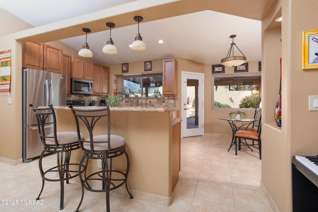 kitchen with a kitchen breakfast bar, decorative backsplash, light tile patterned floors, and stainless steel appliances