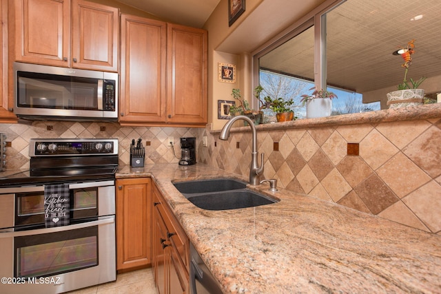 kitchen featuring light stone countertops, sink, decorative backsplash, light tile patterned floors, and appliances with stainless steel finishes