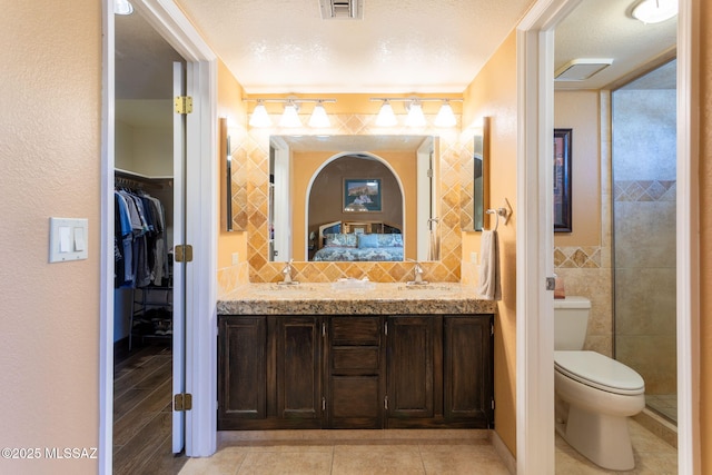 bathroom featuring vanity, tile patterned floors, toilet, a textured ceiling, and tile walls