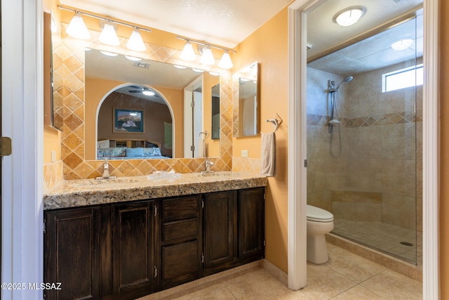 bathroom with tiled shower, tile patterned floors, vanity, and toilet