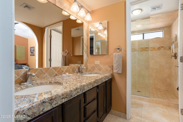 bathroom featuring a tile shower, tile patterned flooring, and vanity