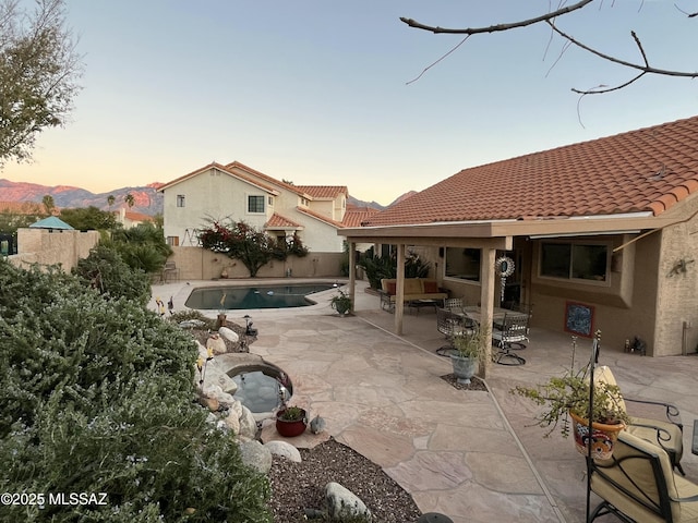 pool at dusk featuring a jacuzzi and a patio