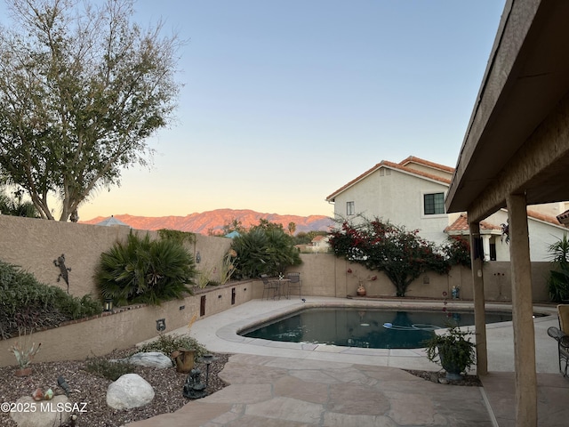 pool at dusk featuring a mountain view and a patio