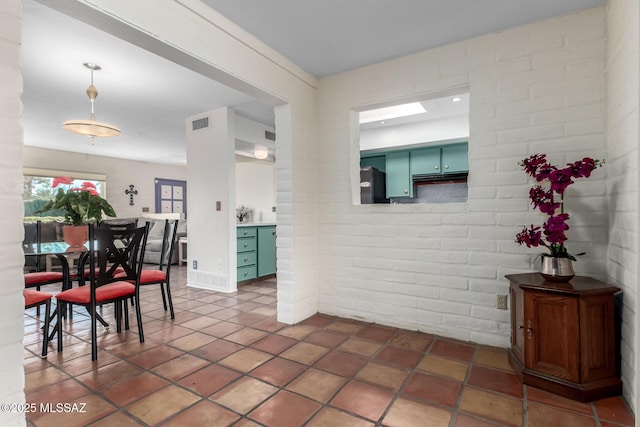 tiled dining room featuring brick wall