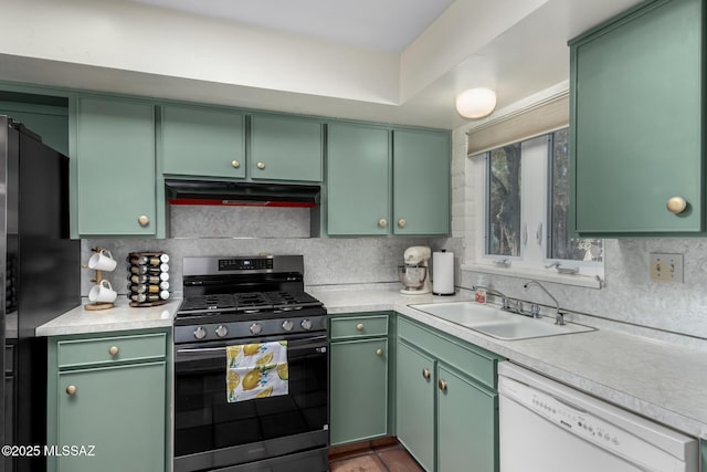 kitchen with black refrigerator, white dishwasher, sink, stainless steel range with gas cooktop, and green cabinets