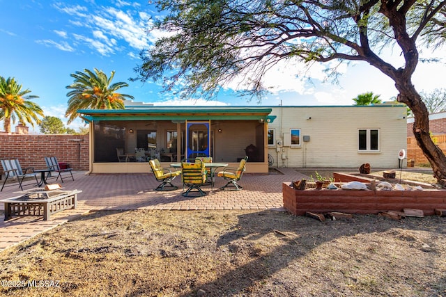 back of house with a sunroom, a fire pit, and a patio area